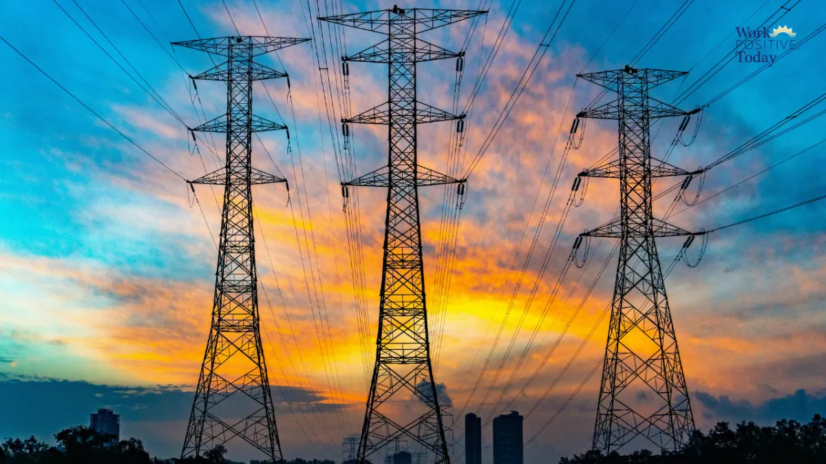 Three high-voltage electrical transmission towers silhouetted against dramatic sunset sky with orange, yellow, and blue clouds, power lines connecting the towers in network, illustrating Chip Higgins' metaphor that culture is the power grid carrying organizational energy, where small breakages stop momentum and 2-3 energy sappers drain talent development for every zapper, with Work Positive Today logo visible.