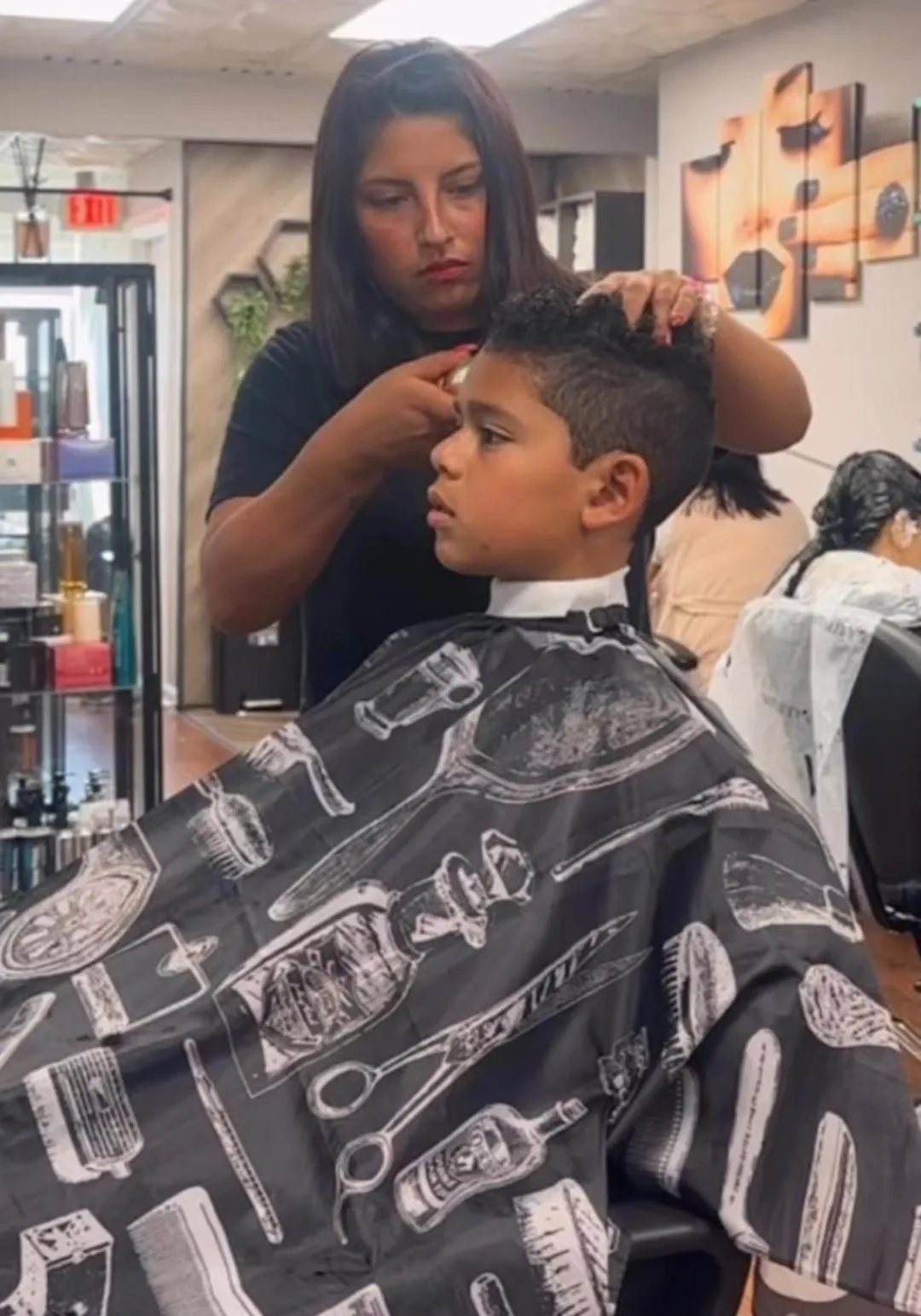 woman barber cutting a young boy's hair