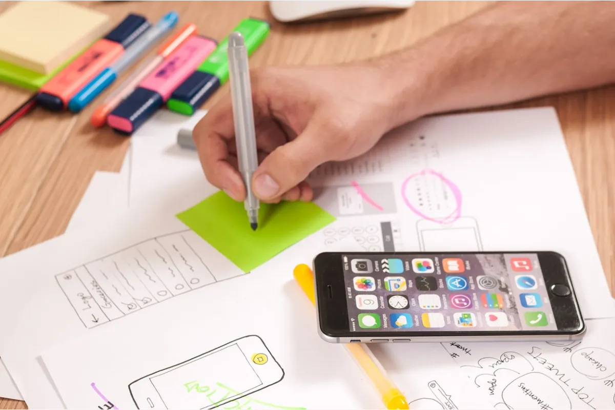 Close-up shot of a professional working on a product wireframe using a smartphone as a guide