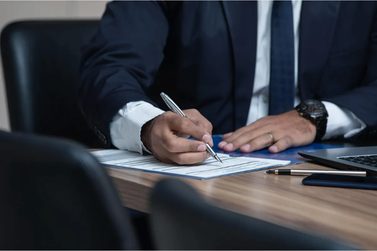 A businessman writing on a document while processing a patent