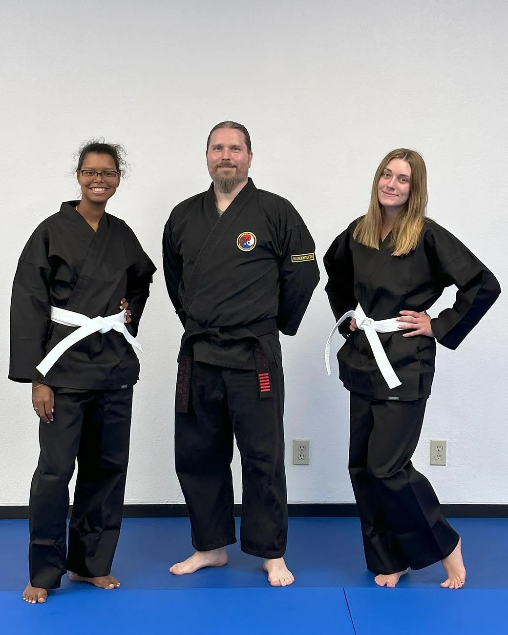 Three adult students posing on the mat at Omega Martial Arts in Plano