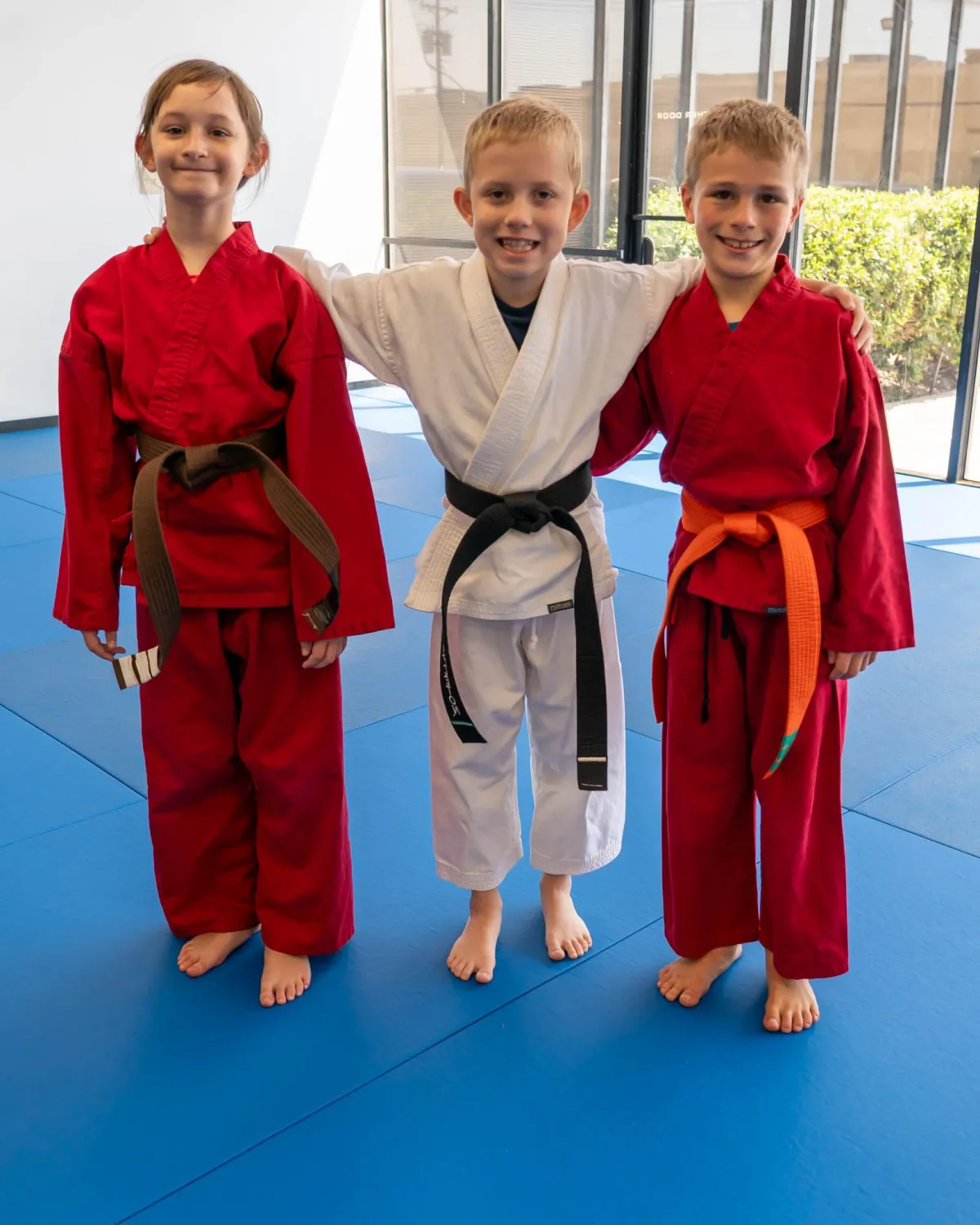 Three young student standing on the mat at Omega Martial Arts in Plano