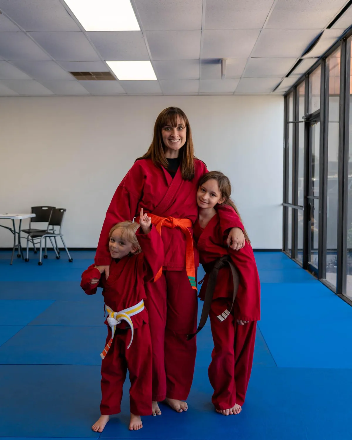 A family of students hugging on the mat at Omega Martial Arts in Plano