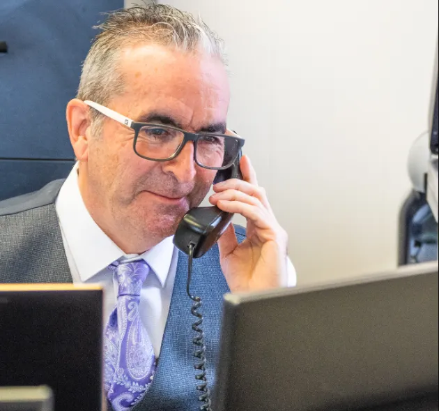 Mortgage advisor with curly blonde hair working on a laptop in a bright office, viewing a mortgage website.