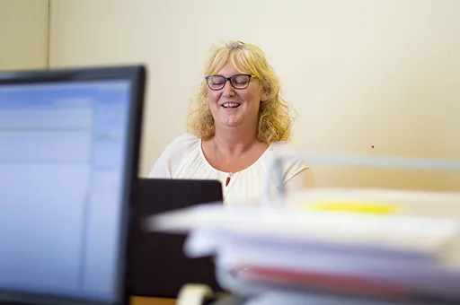 Friendly team member at Aspect Mortgages smiling while working at her desk, supporting clients with their mortgage journey.