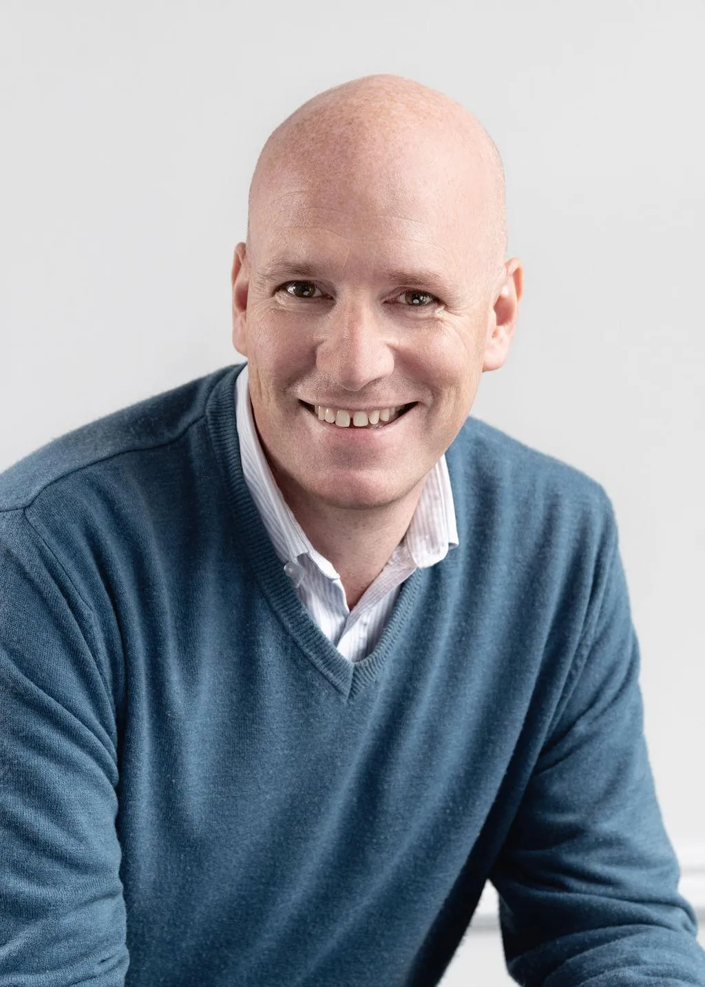 Richard Gill, of Aspect Mortgages in a navy jumper and checked shirt standing against a plain dark background