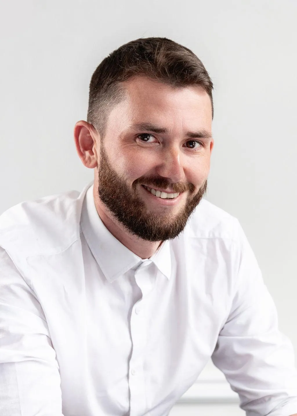 Richard Gill, of Aspect Mortgages in a navy jumper and checked shirt standing against a plain dark background