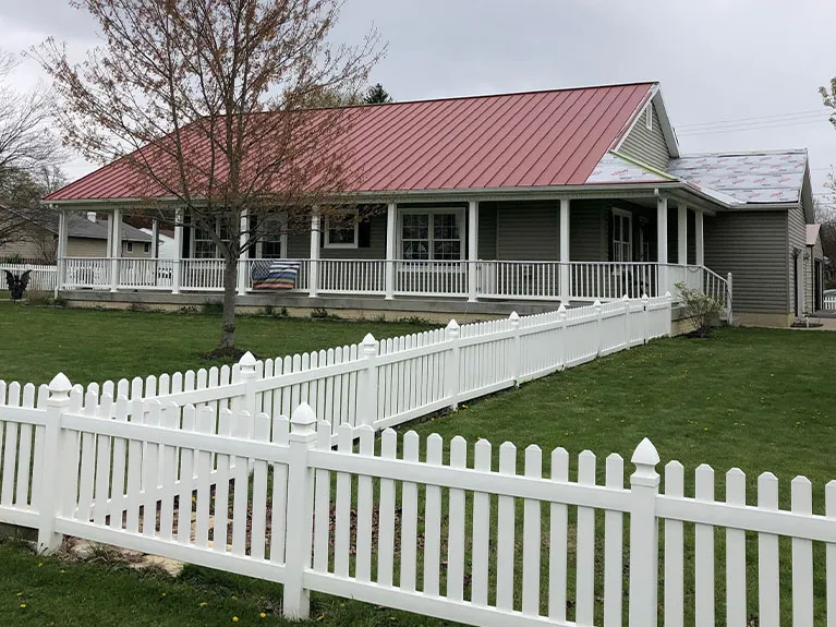 White house with a red standing seam metal roof and front porch