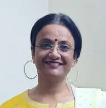 Professional head-and-shoulders portrait of an Indian woman in her thirties, smiling, in business clothing, against a LIGHT softly blurred background