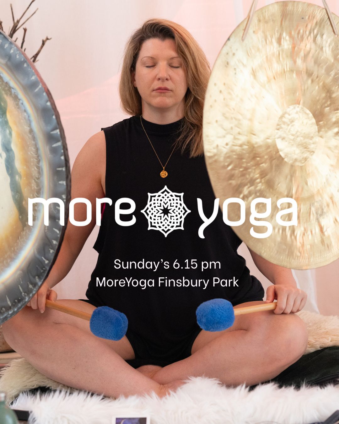 Rachael Welford with eyes closed sitting in front of two large gongs holding beaters with blue tops.