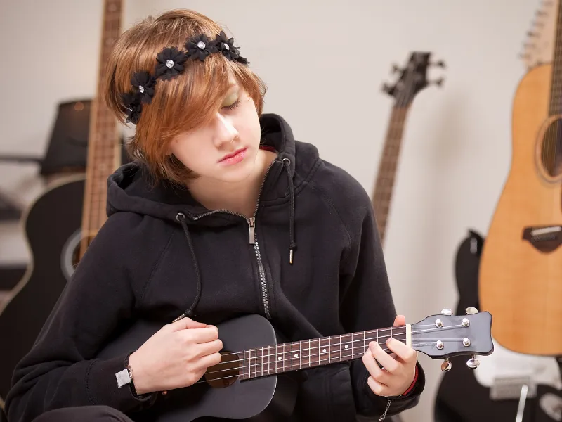 Teen girl surrounded by music, feeling the rhythm of the ukulele during a lesson at Lochwood Academy.