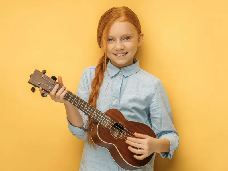 Smiling young girl holding a ukulele at Lochwood Academy, learning music with joy and confidence.