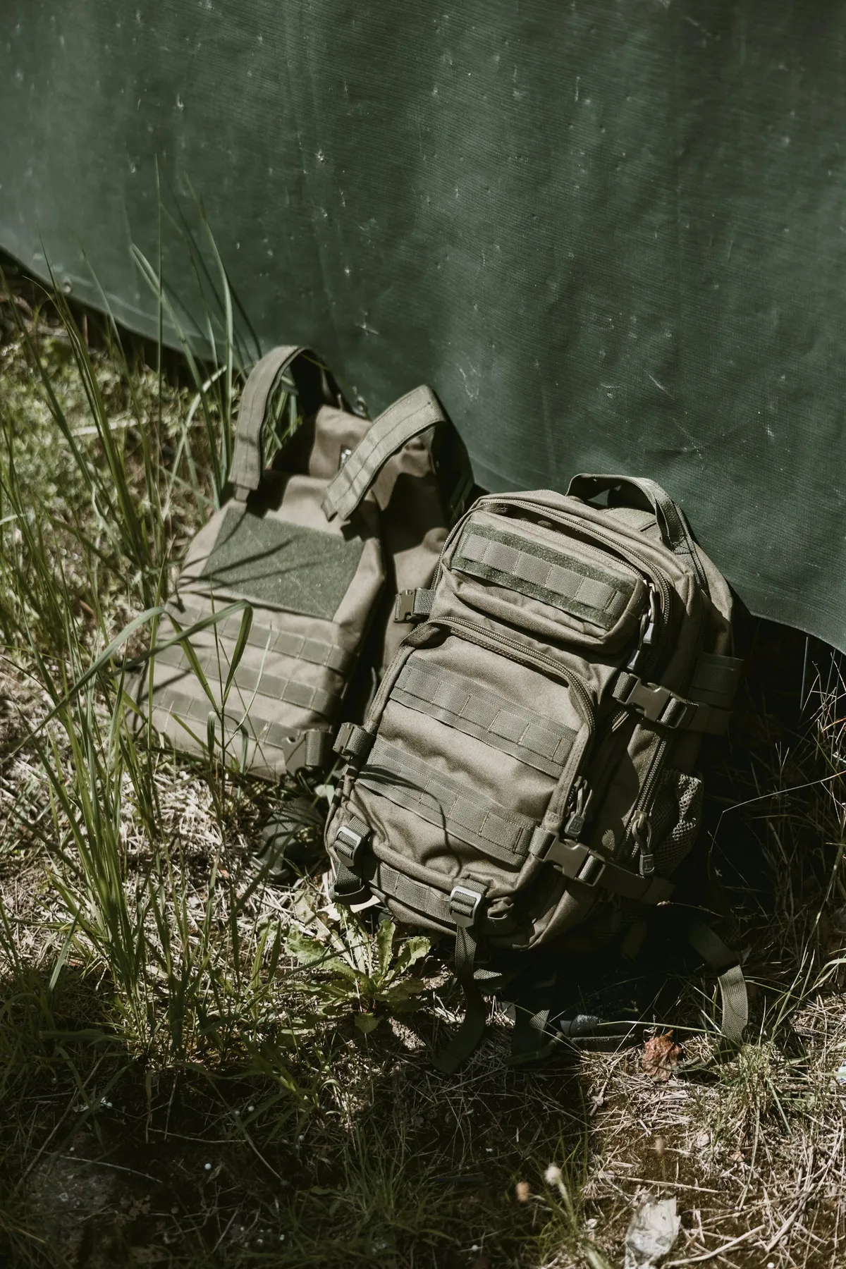 Packed olive-drab tactical backpack and plate carrier staged in the field before a Beacon Rescue deployment