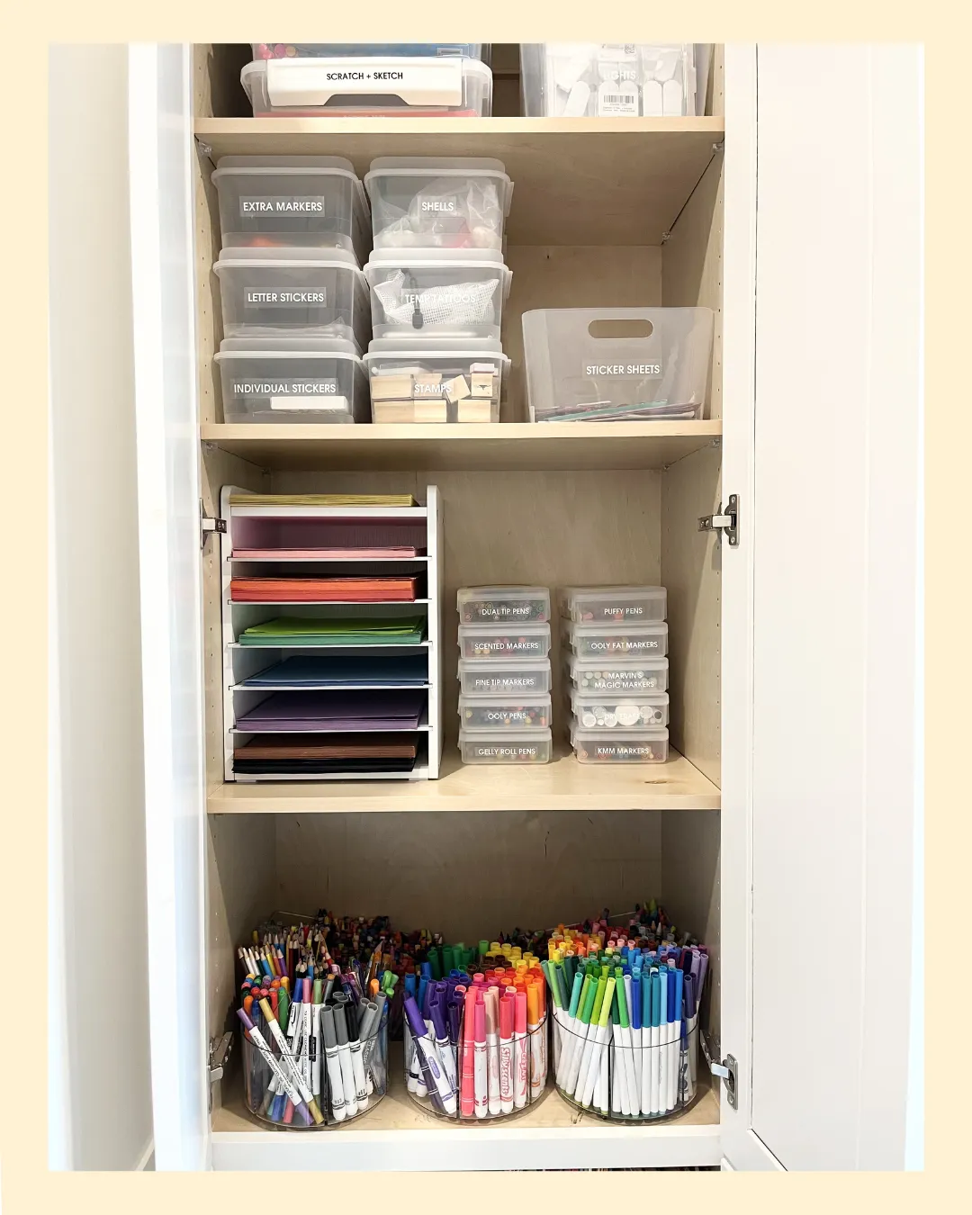 Organized craft cabinet with labeled bins, paper organizers, and color-sorted markers for easy supply storage