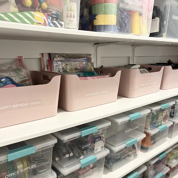 Labeled storage bins and clear containers organizing craft and office supplies for an ADHD-friendly home system