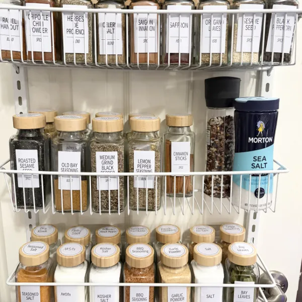 Organized spice rack with labeled glass jars and tiered pantry storage for easy kitchen organization