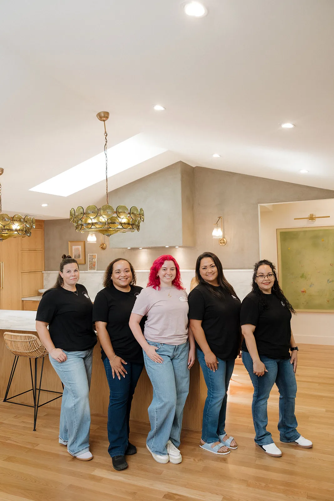 Tidy Crescent Co. team of five organizers in logo T-shirts, with founder Jamie McPhaul in the center, in a bright kitchen