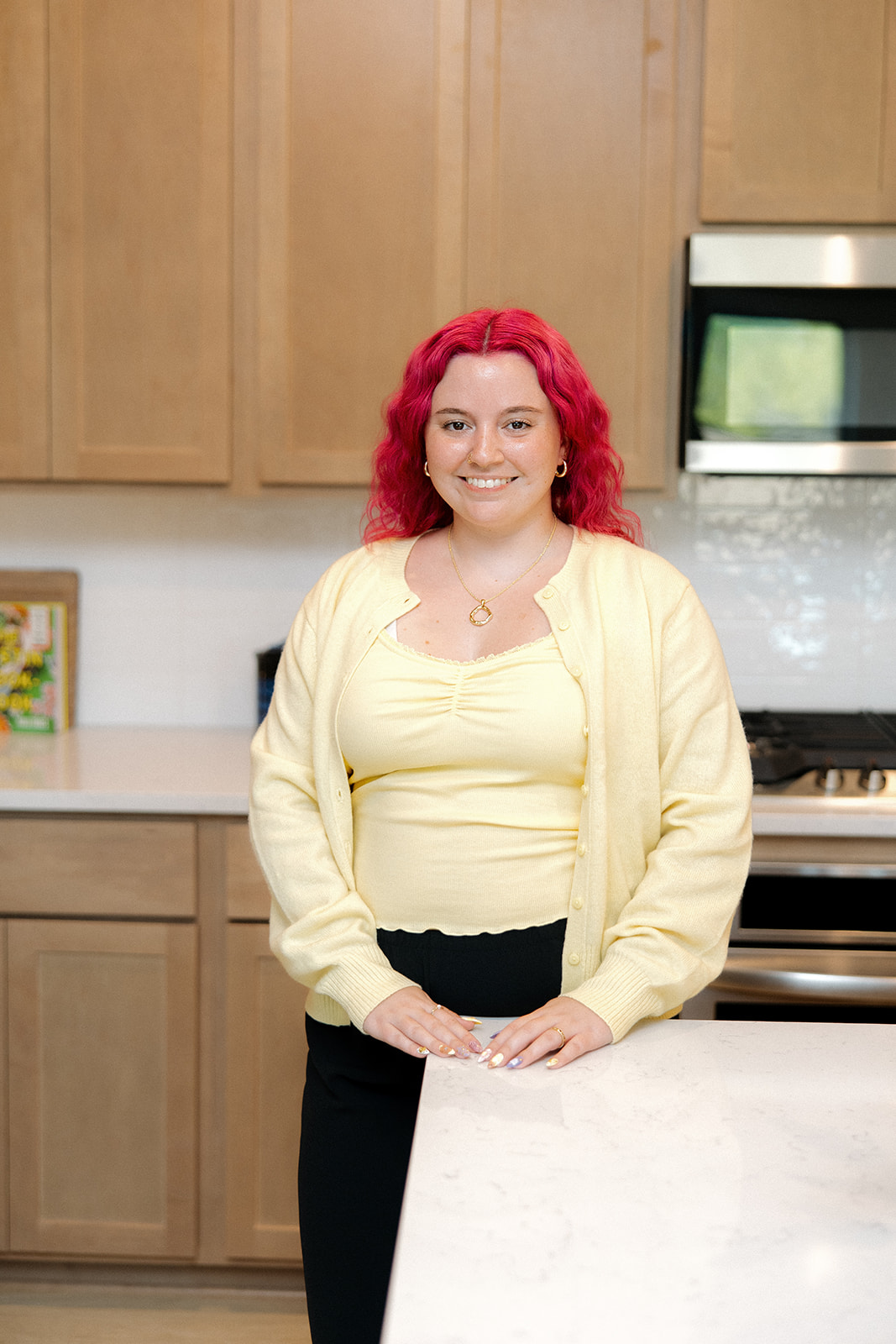 Jamie, founder of Tidy Crescent Co., sitting on a kitchen counter in a bright and organized home