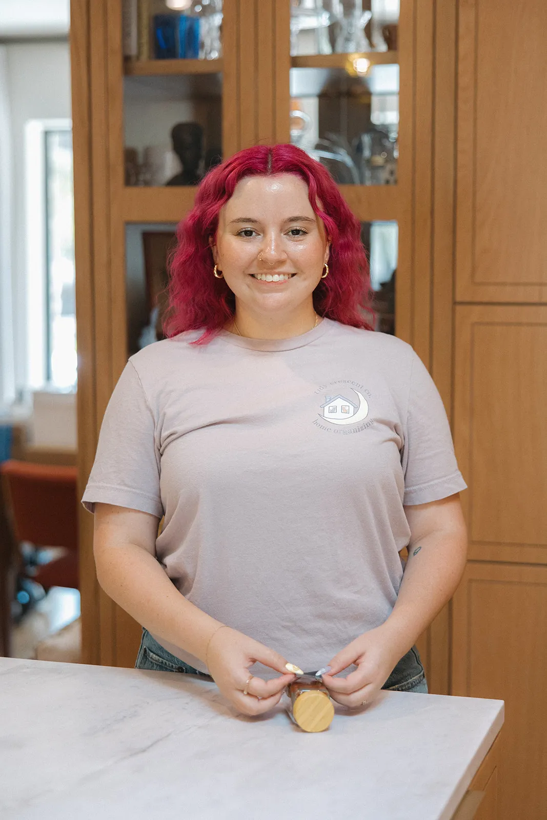 Jamie McPhaul, Austin professional organizer, labeling a pantry jar in a Tidy Crescent Co. logo T-shirt