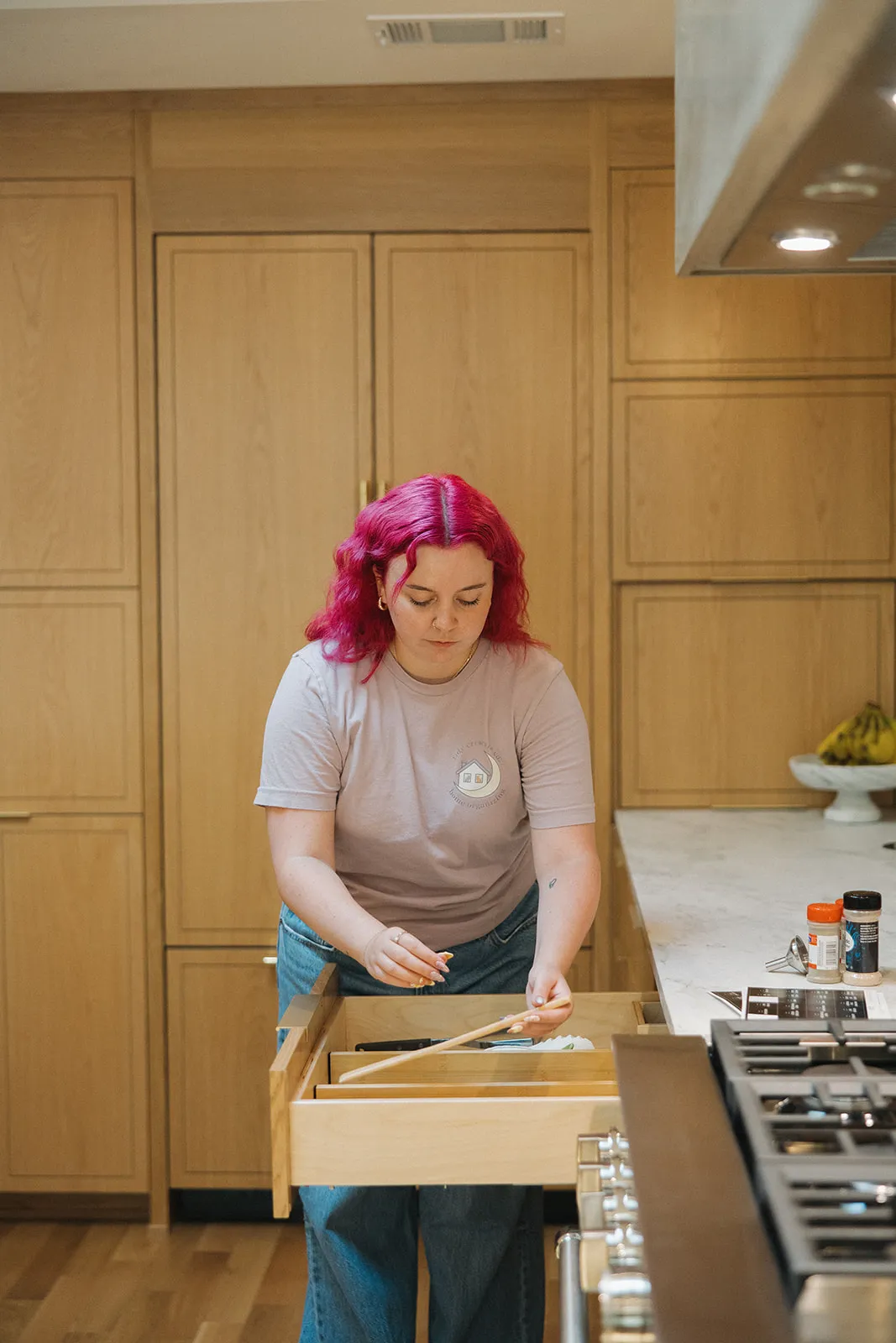 Jamie McPhaul, Austin professional organizer, arranging kitchen utensils in a drawer with wood dividers