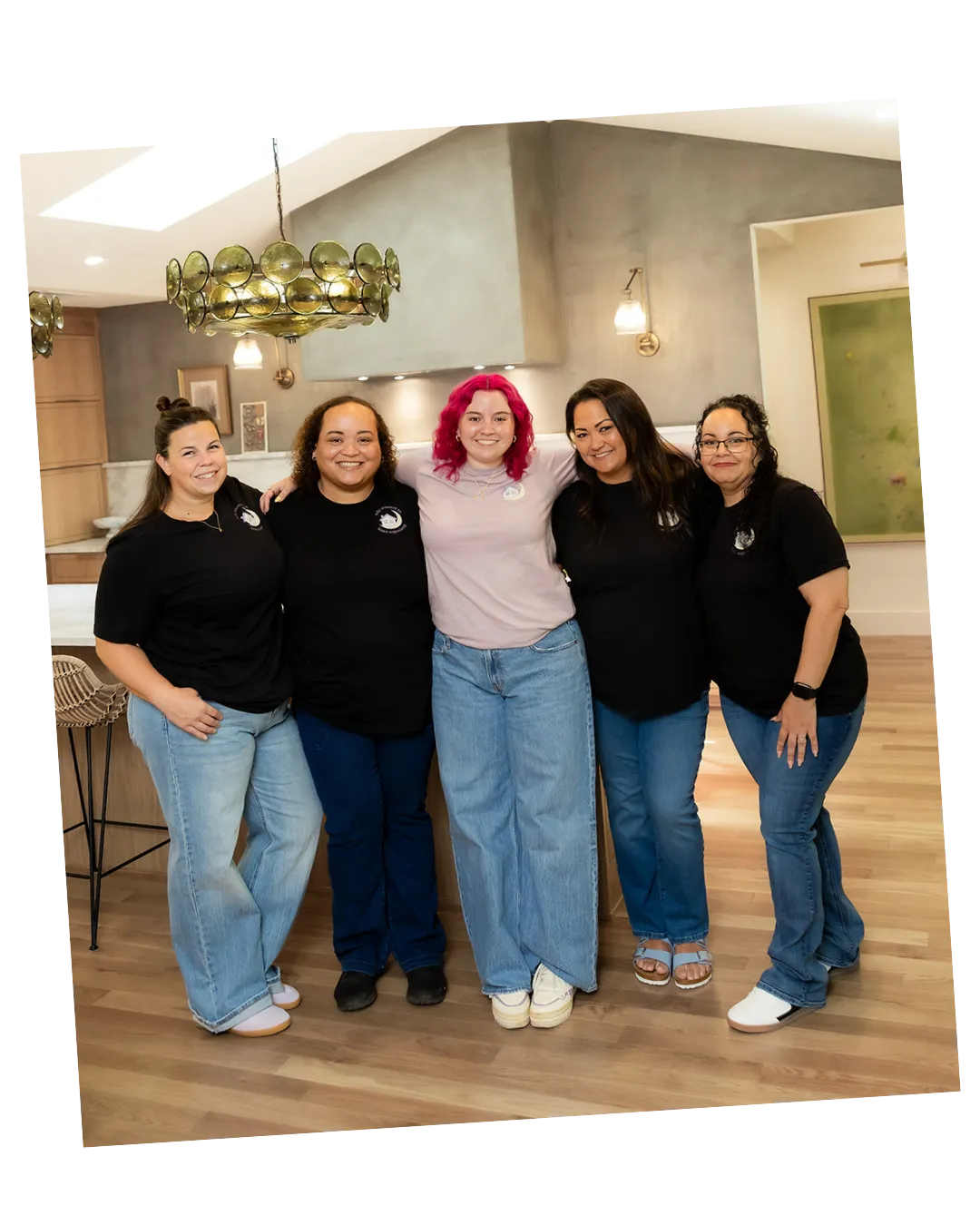 Tidy Crescent Co. team of five arm in arm in logo T-shirts, with founder Jamie McPhaul in the center, in a modern kitchen