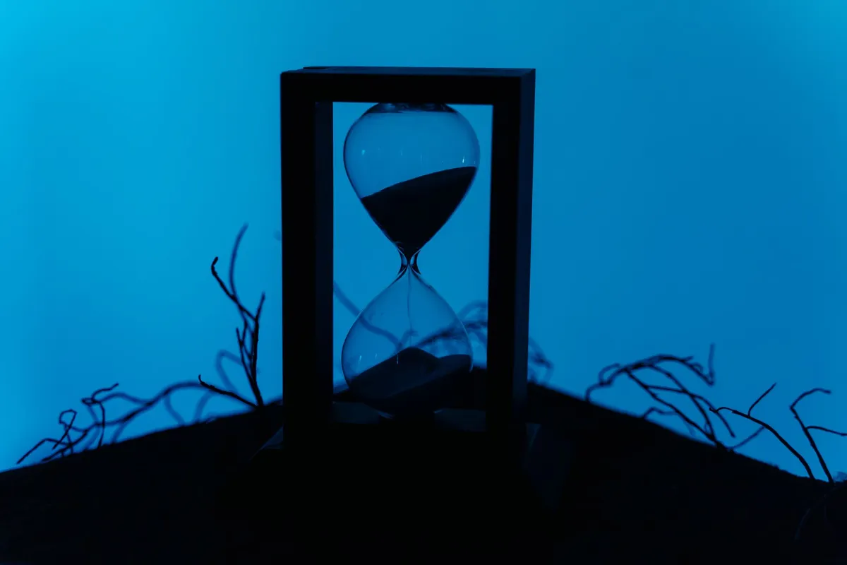 A silhouette of an hourglass set against a vivid blue background, highlighting the passage of time by Ron Lach