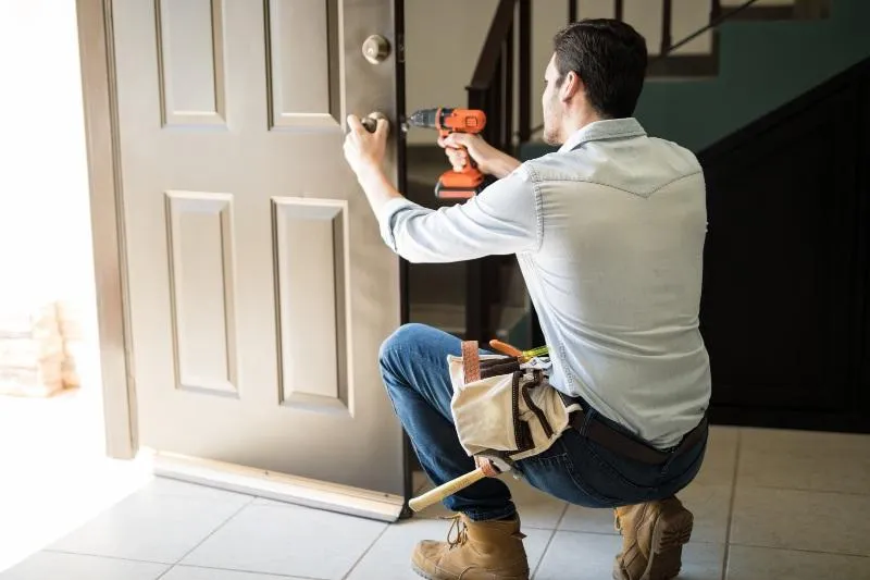 Professional locksmith installing new deadbolt lock on residential front door during rental property turnover in Central Texas