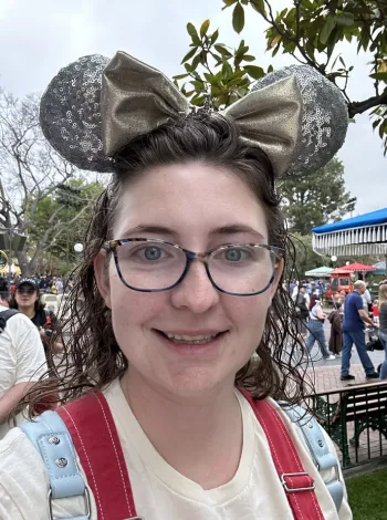 Travel advisor smiling at a Disney park wearing Minnie Mouse ears