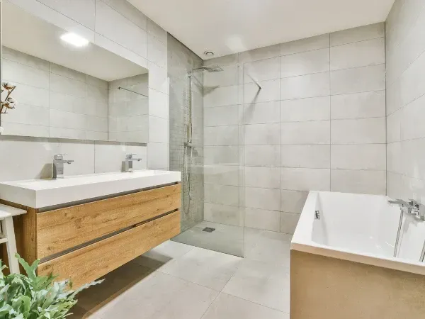 Modern renovated bathroom with glass shower, bathtub, and wooden vanity