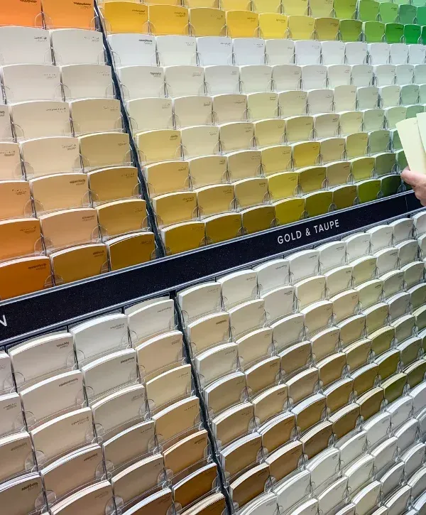 A close-up view of a large display of various gold and taupe color paint swatches in a hardware store.