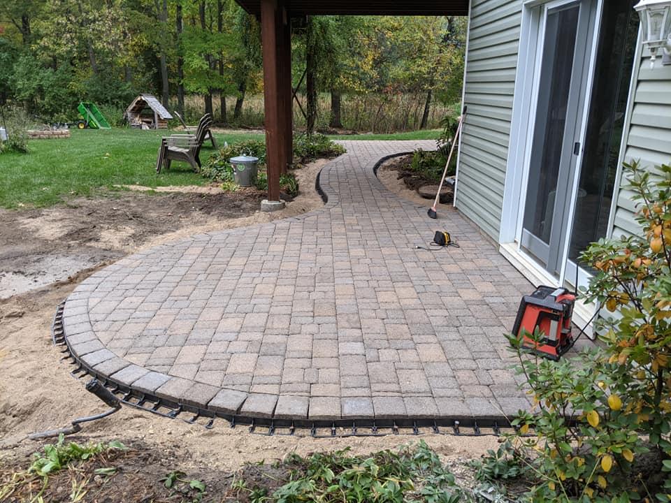 Curved paver walkway and patio under construction outside residential home in MN