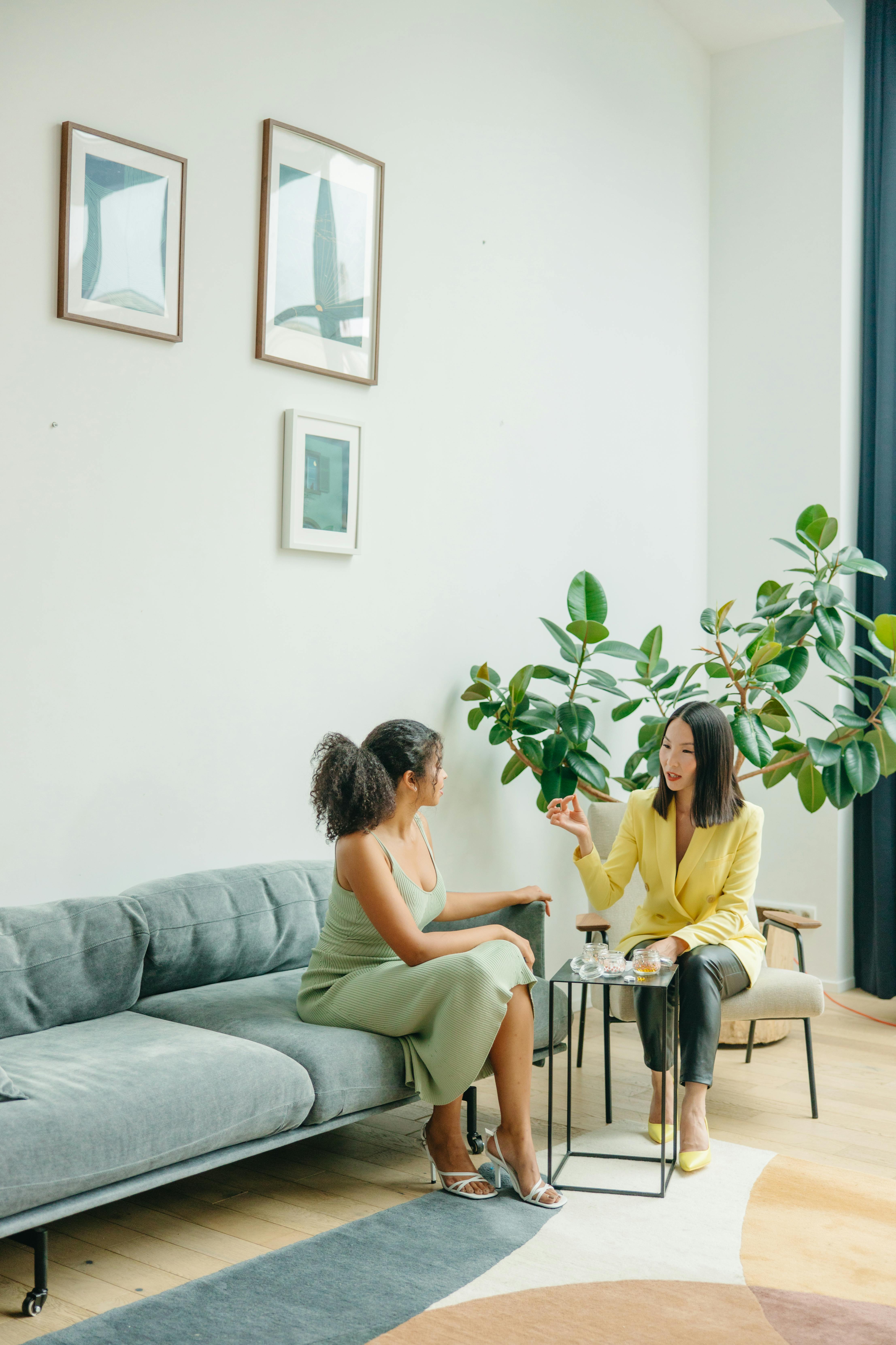 Two women engaging in a supportive therapy session on a green sofa, representing the transition from overwhelmed to grounded.