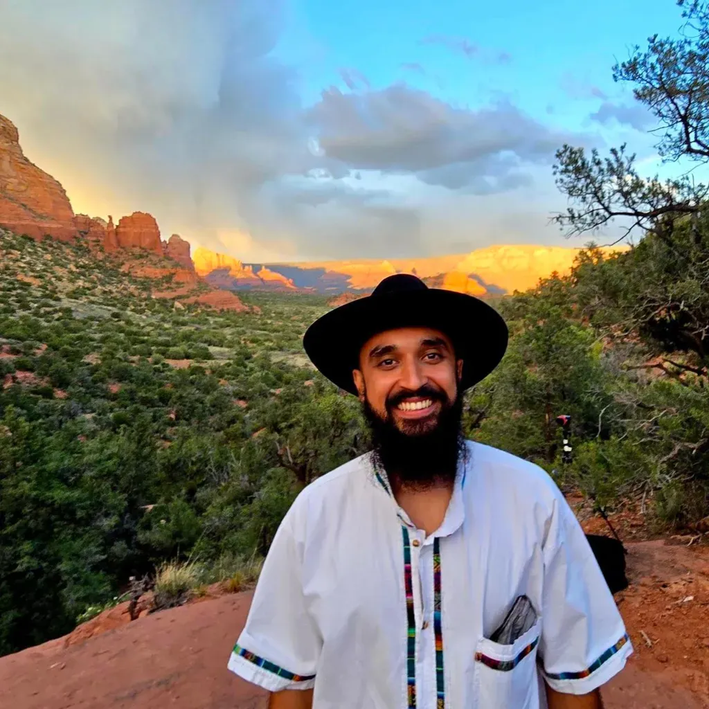 Men's coach, Michael, smiling at the camera with the beautiful Sedona scenery in the background.