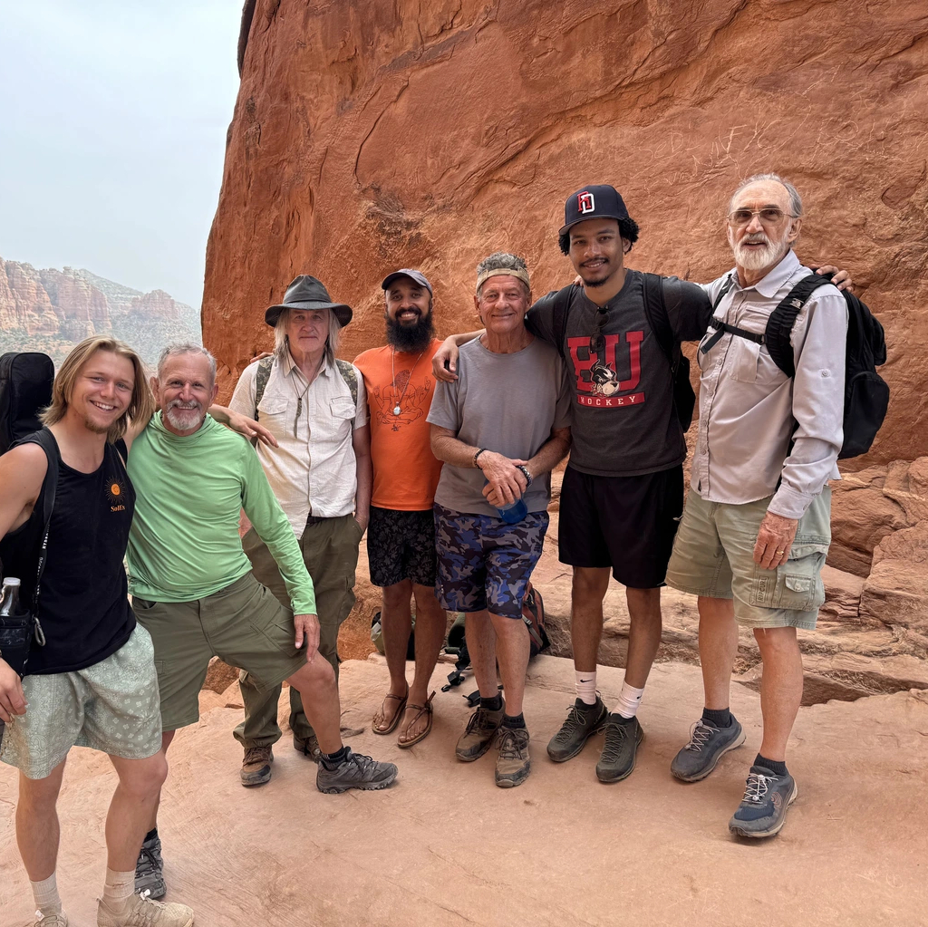 All-inclusve spirital retreat in Sedona, Arizona. Group of 7 men posing for a photo during a hike through the scenery.