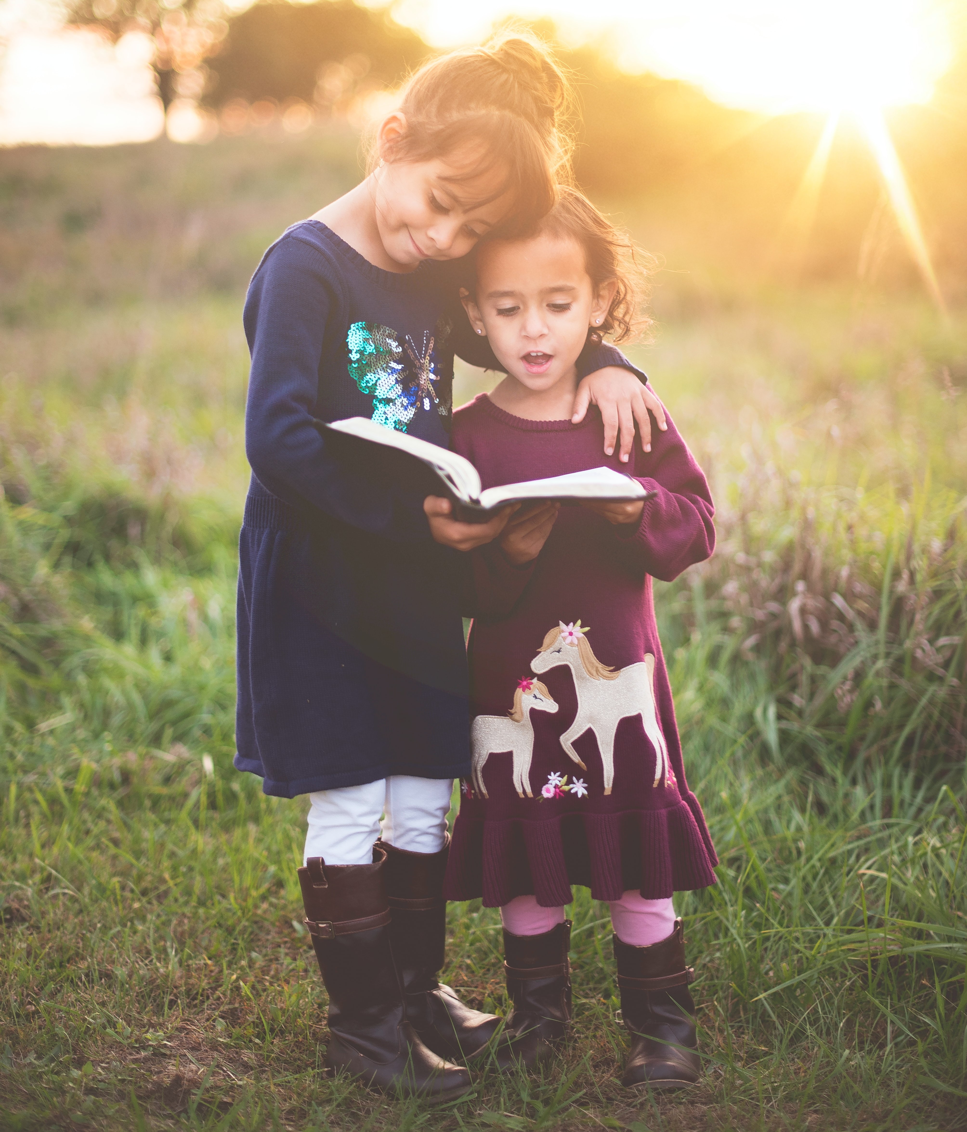 Two young girls reading a book with confidence after completing a Davis Foundations literacy program in the Wellington region.