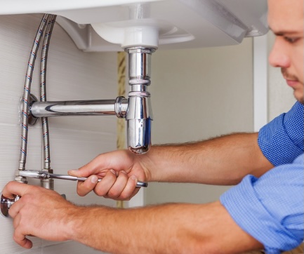 Advantage HPE plumber repairing residential plumbing under a sink for a homeowner on the Emerald Coast of Florida.