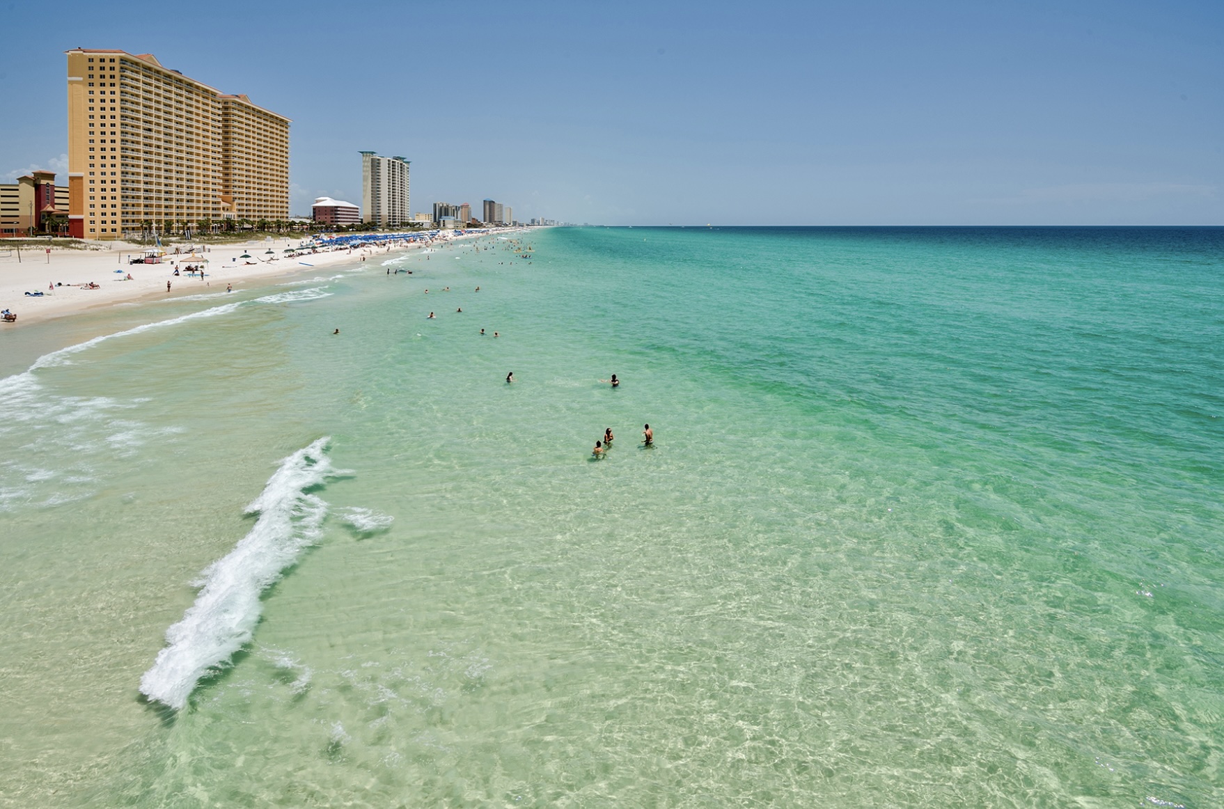 Aerial view of Panama City Beach, Florida featuring white sand beaches, emerald Gulf waters, and beachfront condominiums along the shoreline
