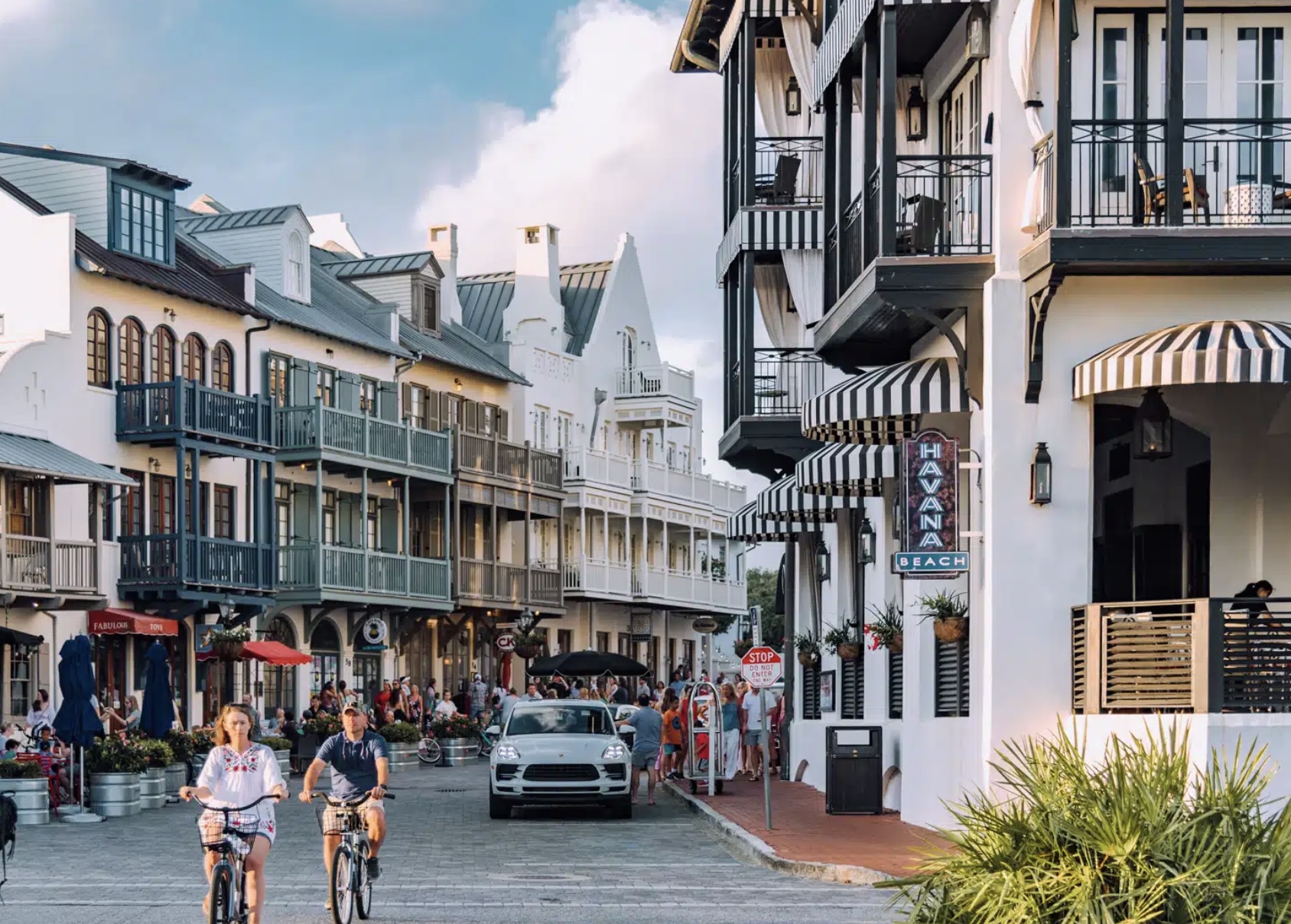 Streetscape in Rosemary Beach, Florida with coastal architecture, shops, and people biking through the town center.