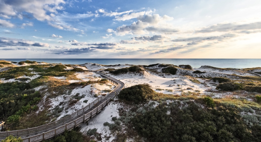 Wooden boardwalk winding through coastal sand dunes toward the Gulf of Mexico in WaterSound, Florida.