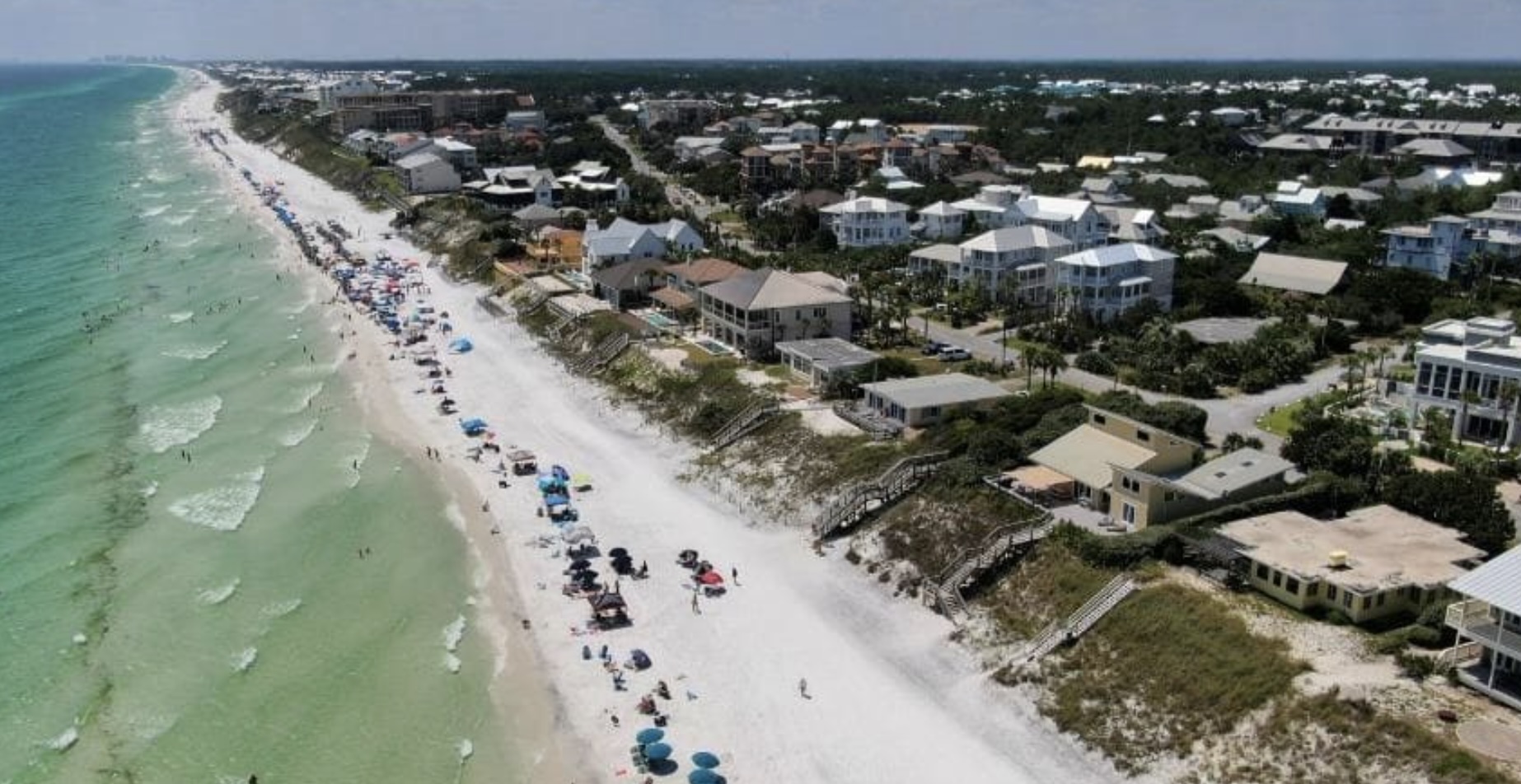 Aerial view of Blue Mountain Beach, FL showing white sand shoreline, emerald Gulf waters, and beachfront homes along Scenic Highway 30A.