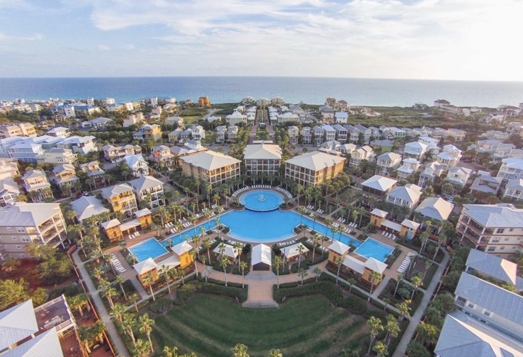 Aerial view of Seacrest Beach, Florida showing resort-style community with central pool, palm-lined pathways, coastal homes, and the Gulf of Mexico in the background
