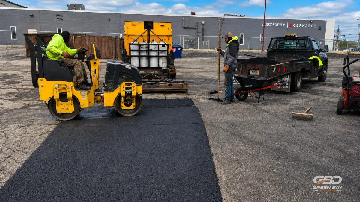 Paving crew repairing damaged section in the middle of a residential driveway