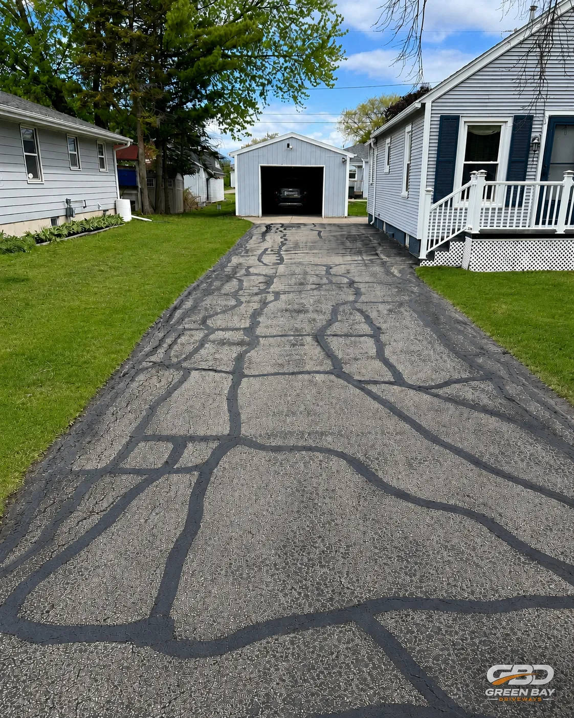 Driveway crack repair in progress with cracks filled and prepped for sealing