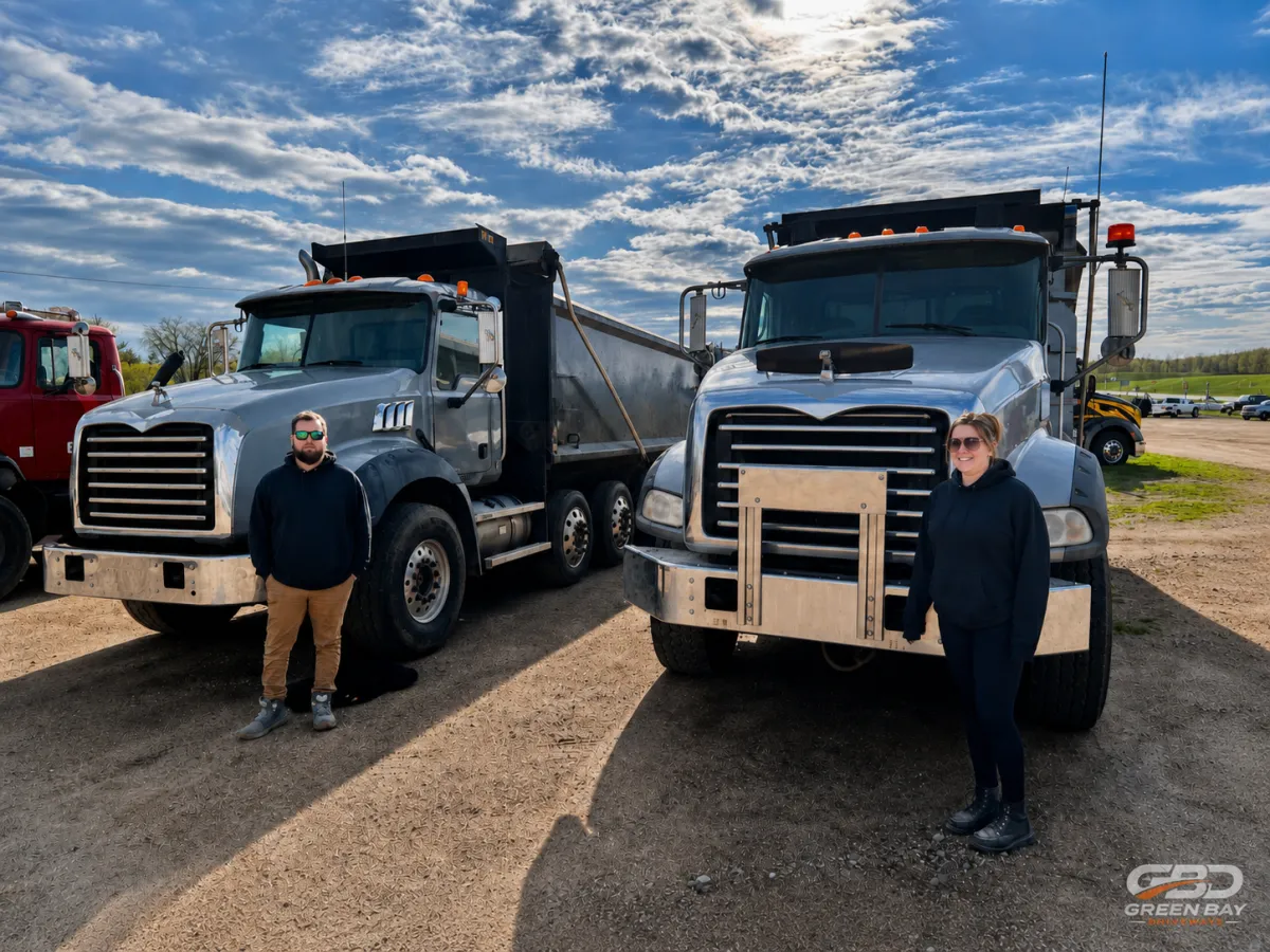 Green Bay Driveways crew standing with commercial dump trucks at a paving and concrete job site