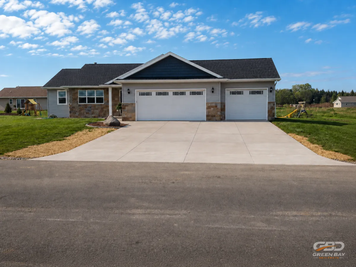 Concrete driveway installation in front of a Green Bay area home with a clean finished surface and attached garage