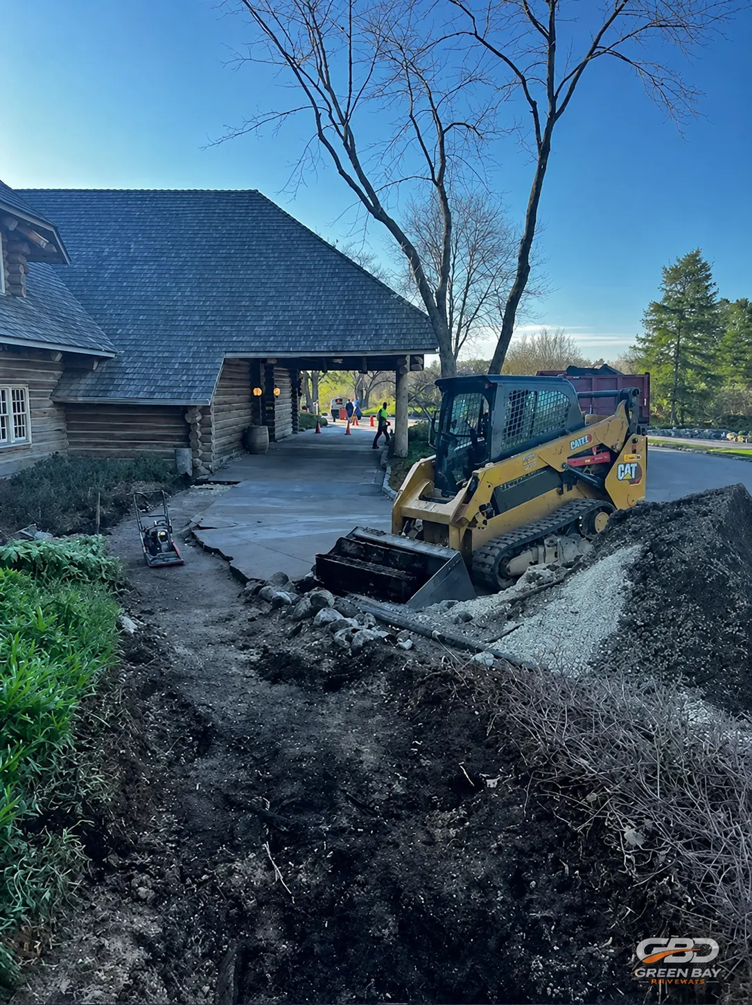 Skid steer removing an old driveway during a driveway replacement project in Green Bay, Wisconsin
