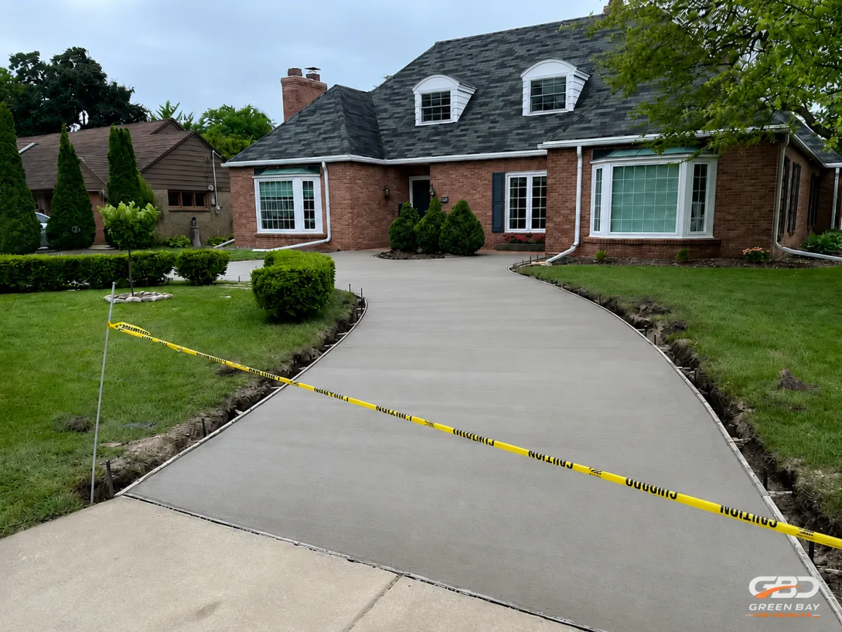 Freshly poured concrete driveway with wooden forms being removed during curing process