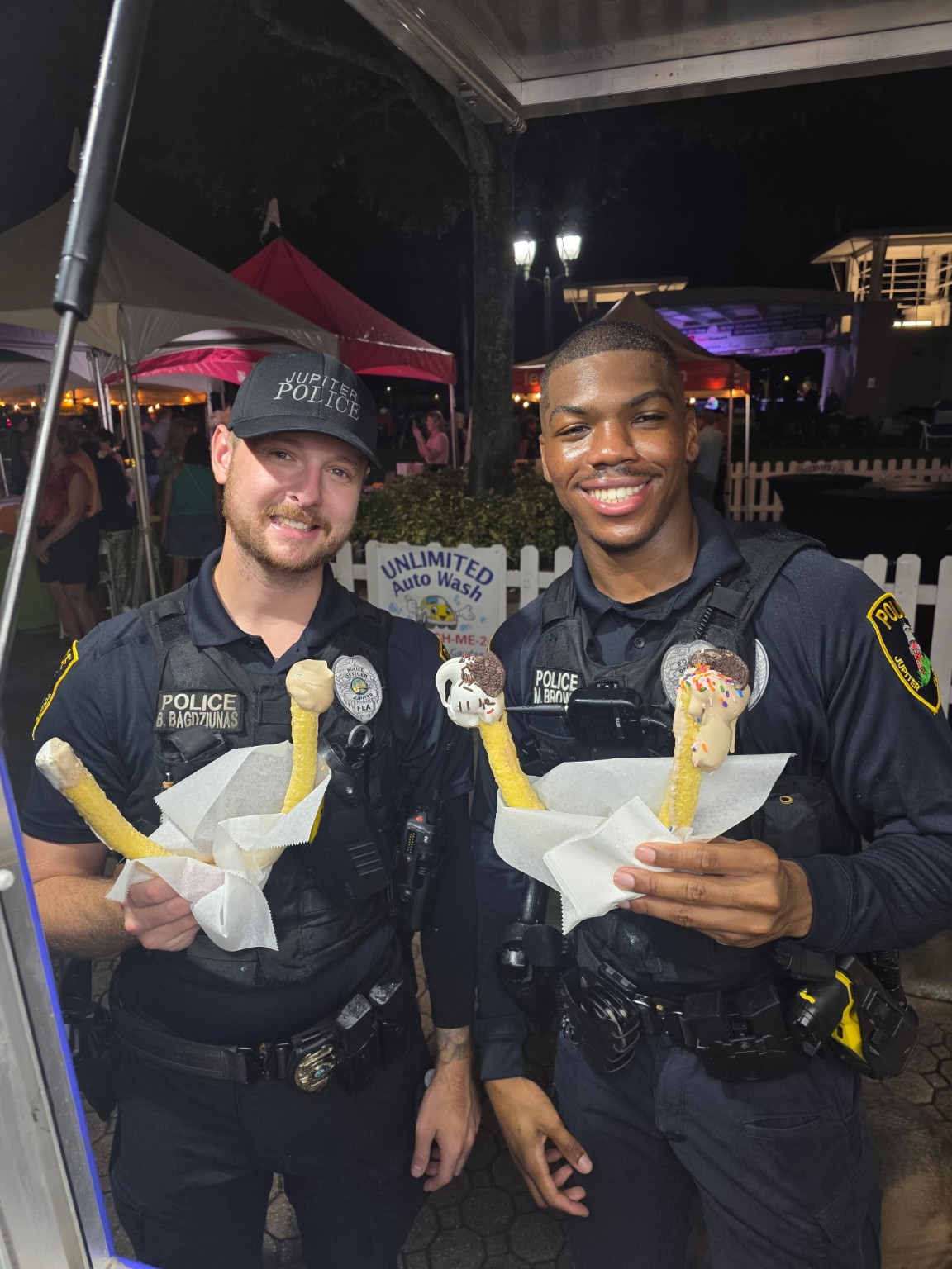 Two police officers holding signature U-Cones from I Love U Ice Cream at a nighttime community event
