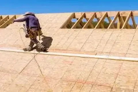 Roofer installing OSB deck sheathing over new construction roof framing in Brooklyn Park