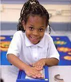 Girl folds paper while watching teacher on laptop